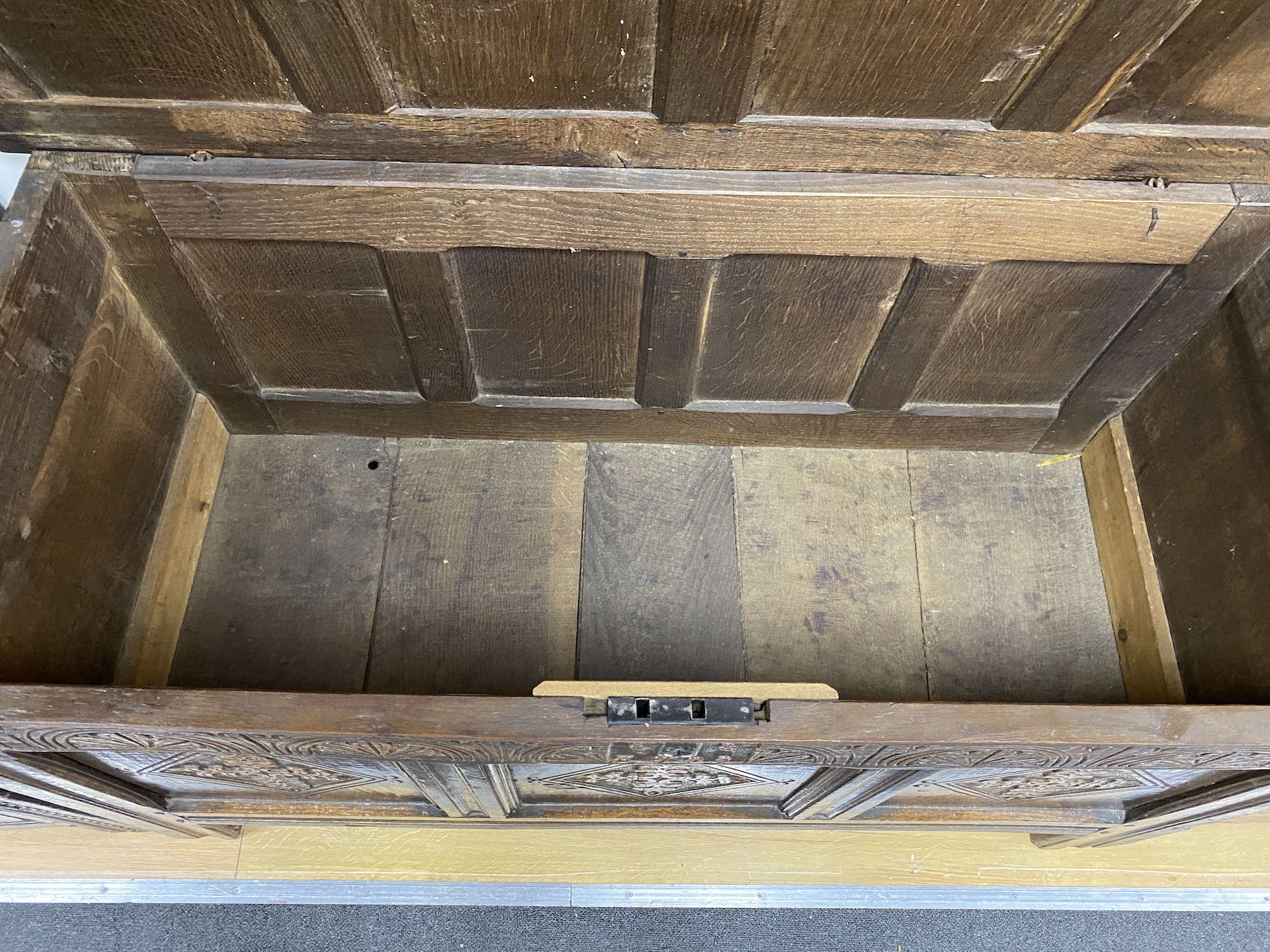 A late 17th century oak coffer, with a panelled top and lozenge carved front, length 128cm, depth 56cm, height 70cm